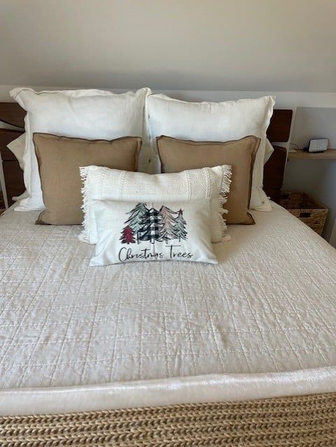 A bed with a christmas tree pillow on it