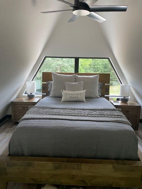 A bedroom with a bed , nightstands , and a ceiling fan.