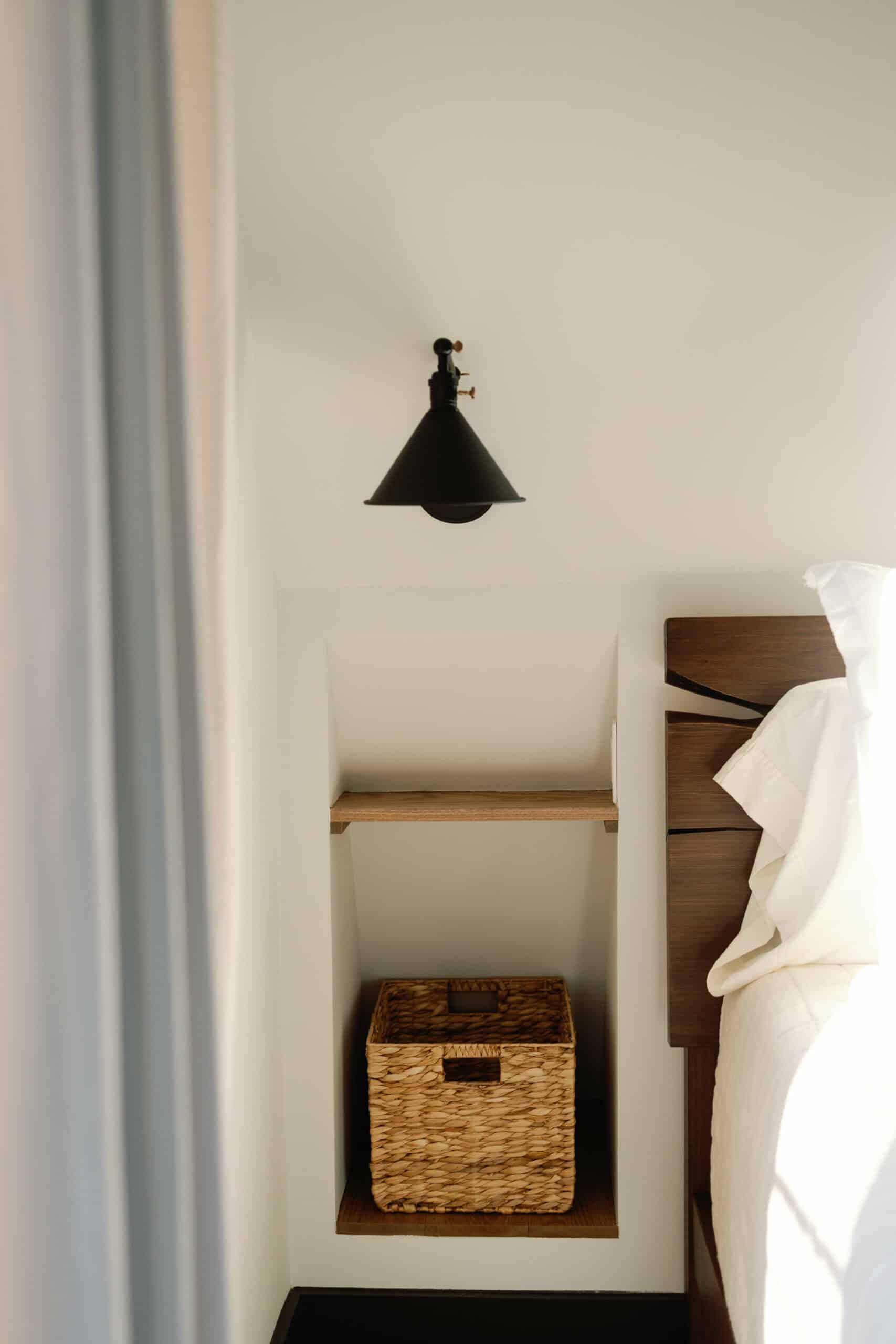 There is a basket on the shelf next to the bed.