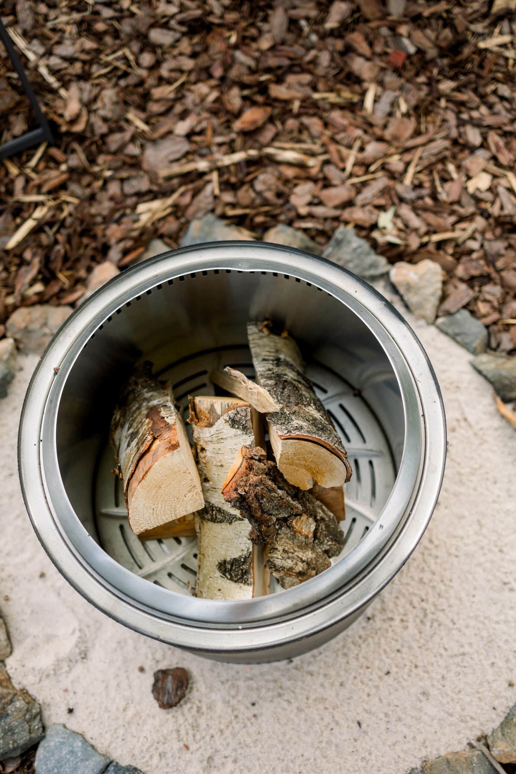 A pot filled with logs is sitting on top of a pile of wood chips.