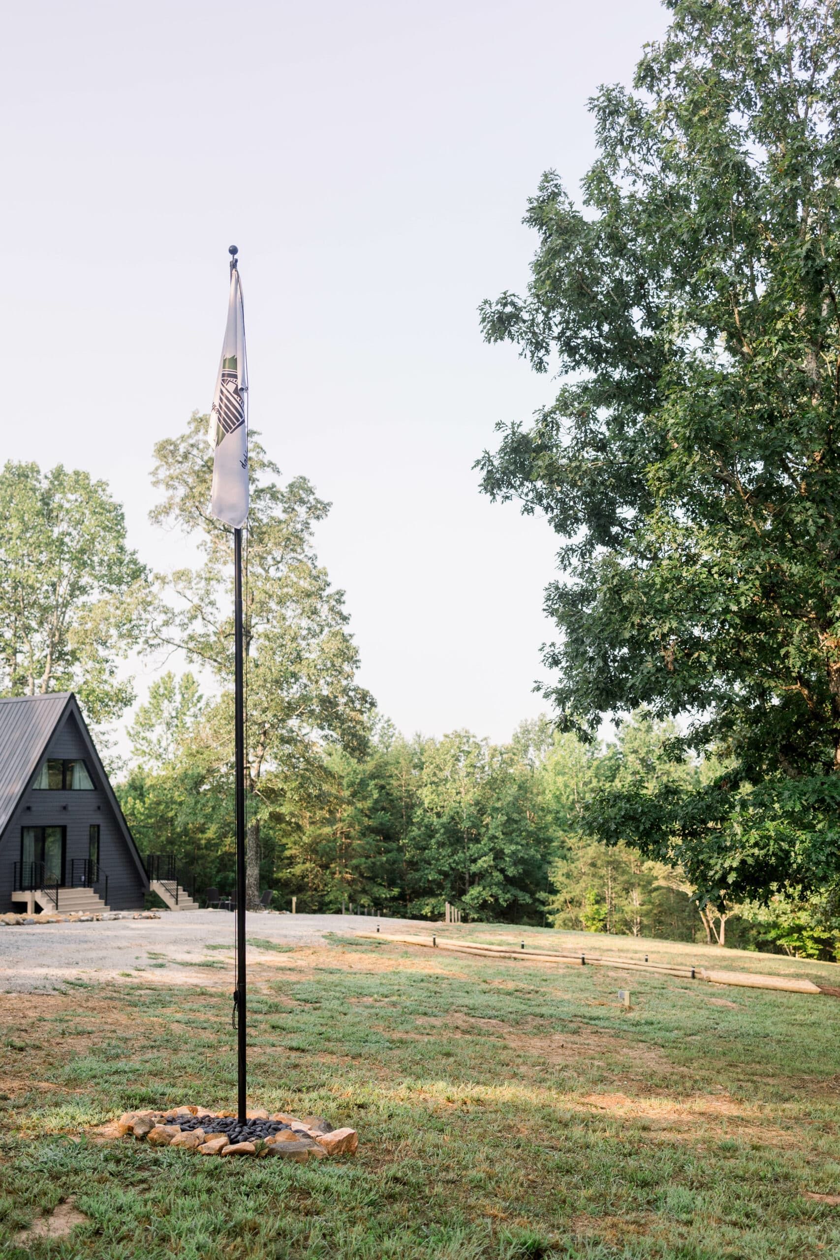 A flag is flying in a field in front of a house.
