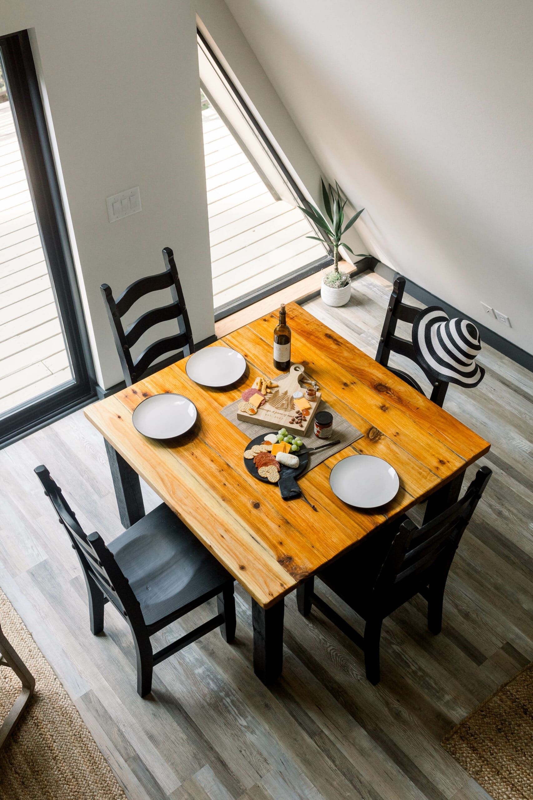 An aerial view of a wooden dining table with four chairs and plates on it.