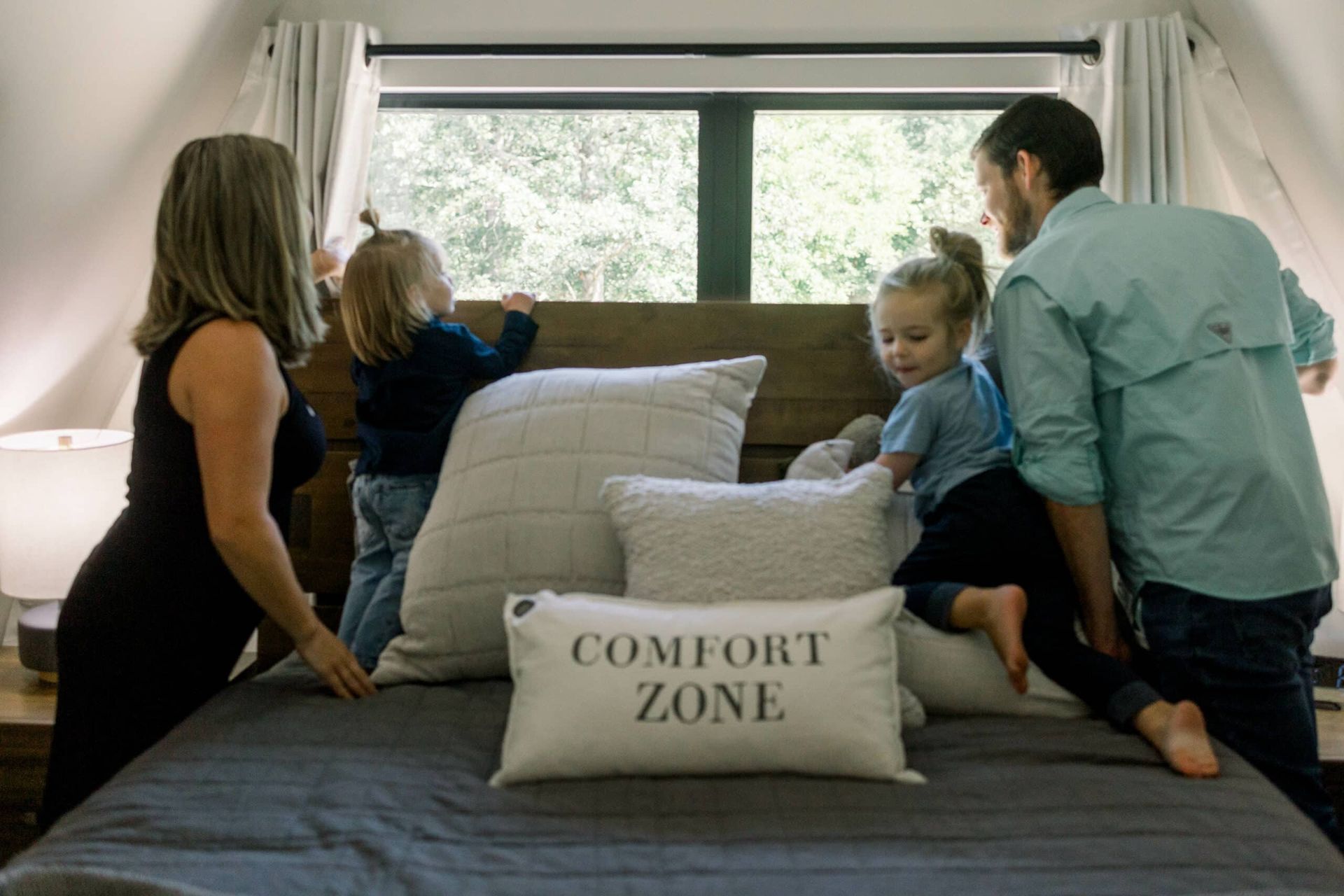 A family is sitting on a bed with a comfort zone pillow.