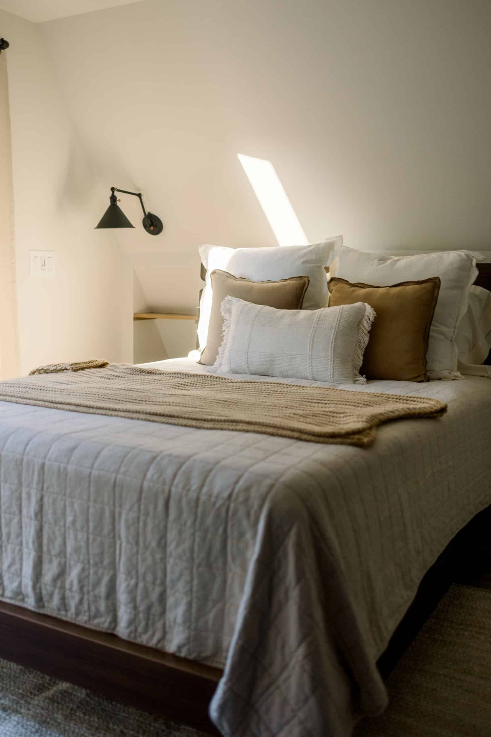 A bed with a white blanket and brown pillows in a bedroom