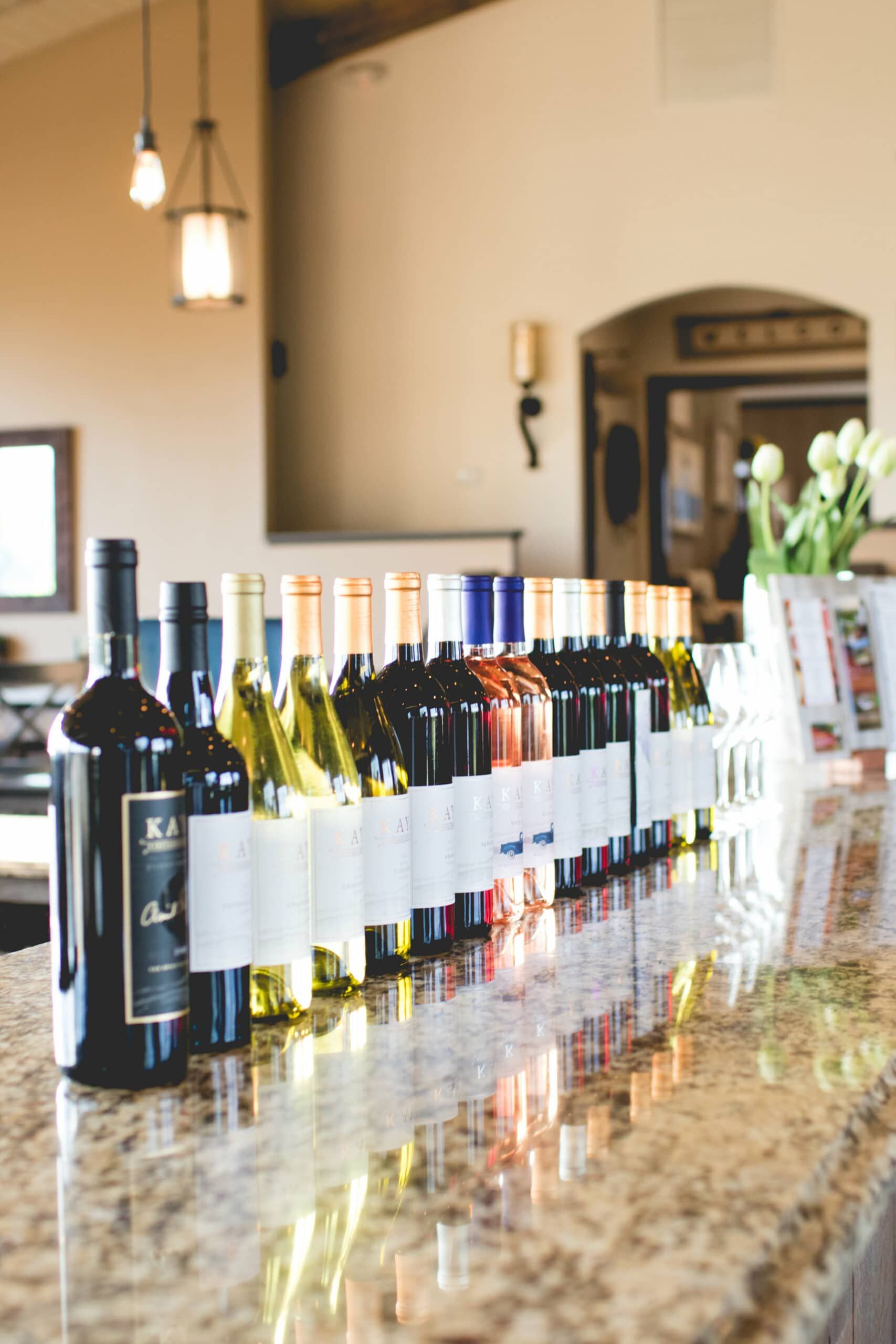 A row of wine bottles are lined up on a counter.