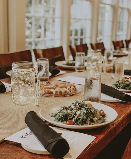 A wooden table with plates of food and glasses on it.
