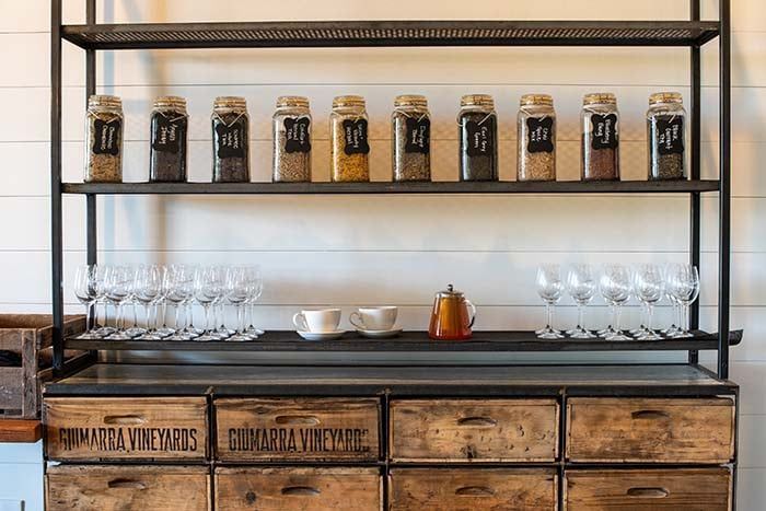 A shelf with jars of spices and wine glasses on it.