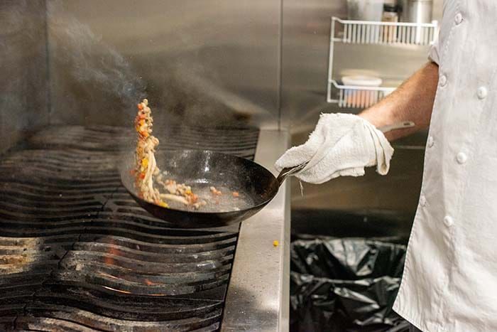 A chef is cooking food in a frying pan in a kitchen.