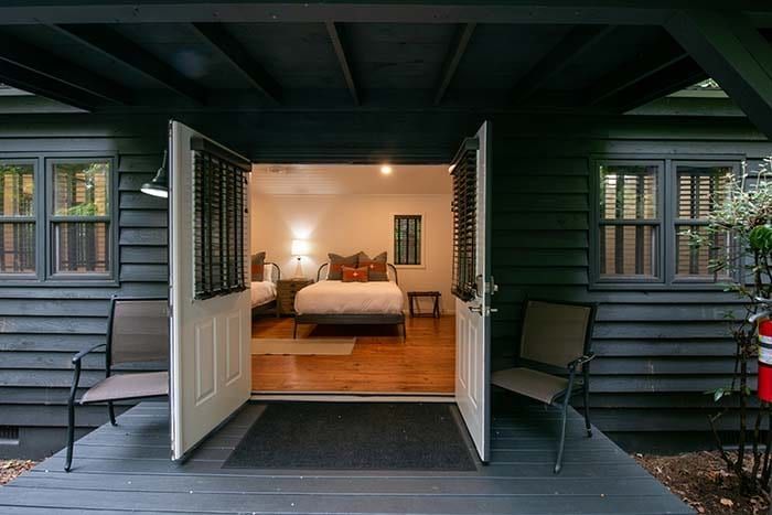 The door is open to a bedroom with a bed and chairs.