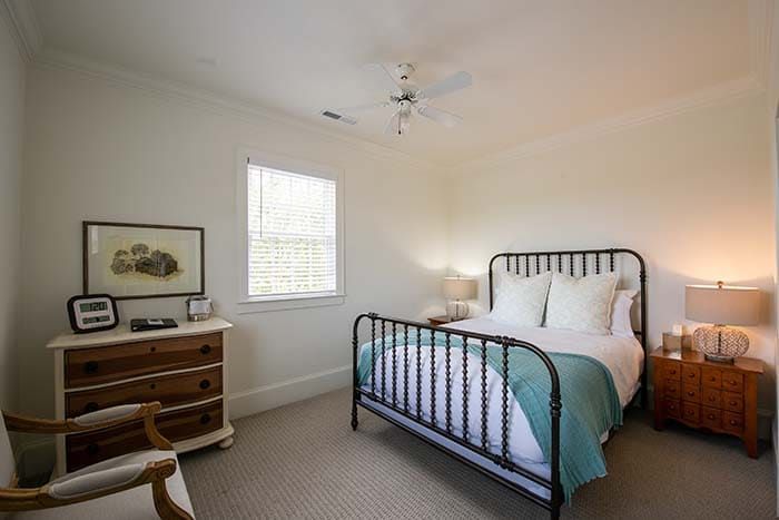 A bedroom with a bed , dresser , nightstand , chair and ceiling fan.