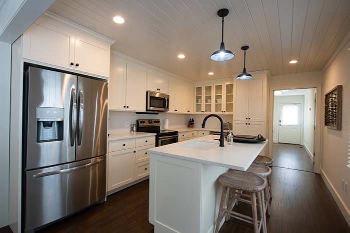 A kitchen with white cabinets , stainless steel appliances , and a large island.