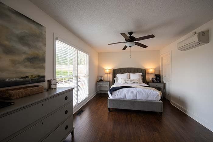 A bedroom with a bed , dresser , and ceiling fan.