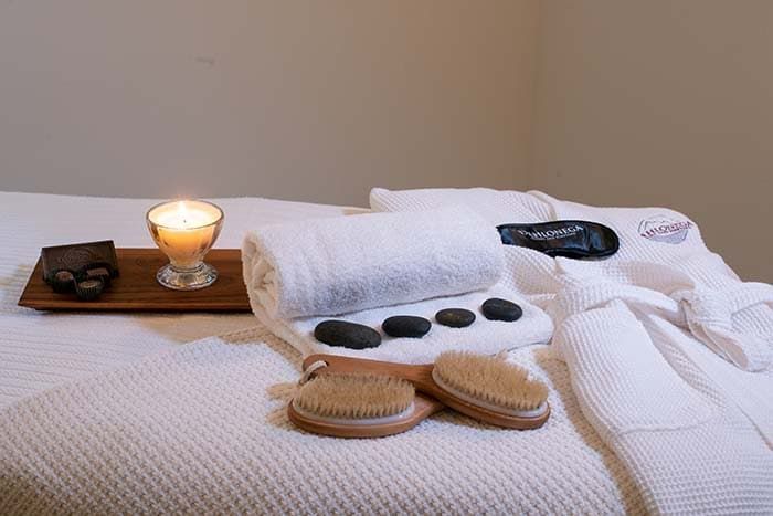 A bed with towels , brushes , candles and rocks on it.