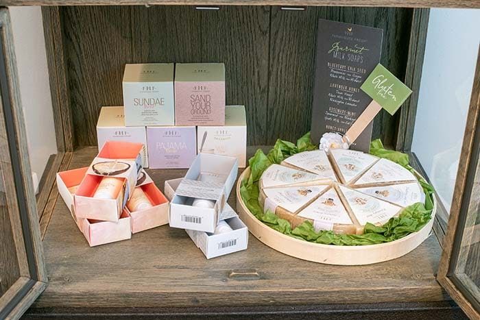 A wooden shelf with boxes of soap and a slice of cake on it.