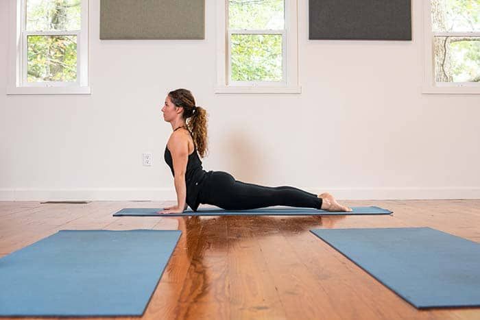 A woman is doing yoga on a blue mat in a room.