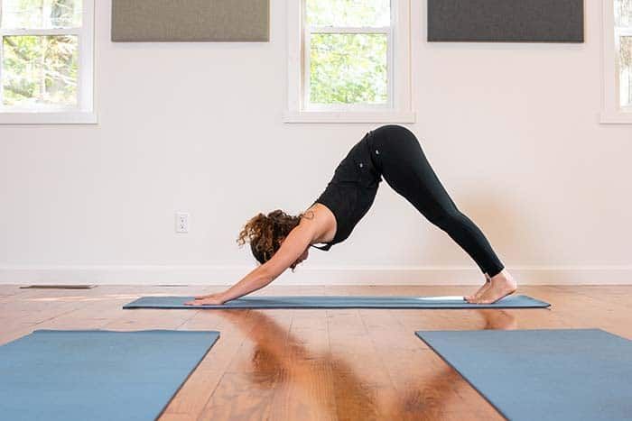 A woman is doing a yoga pose on a yoga mat in a room.