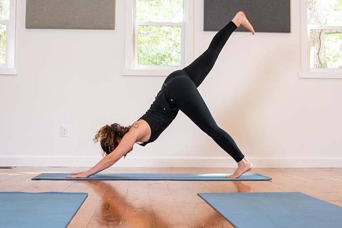 A woman is doing a yoga pose on a yoga mat in a room.