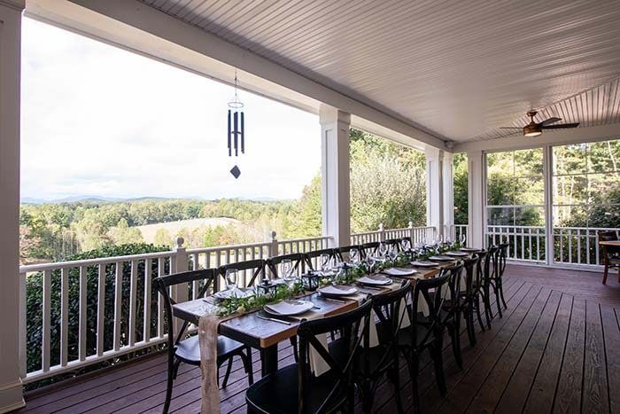 There is a long table and chairs on the porch.