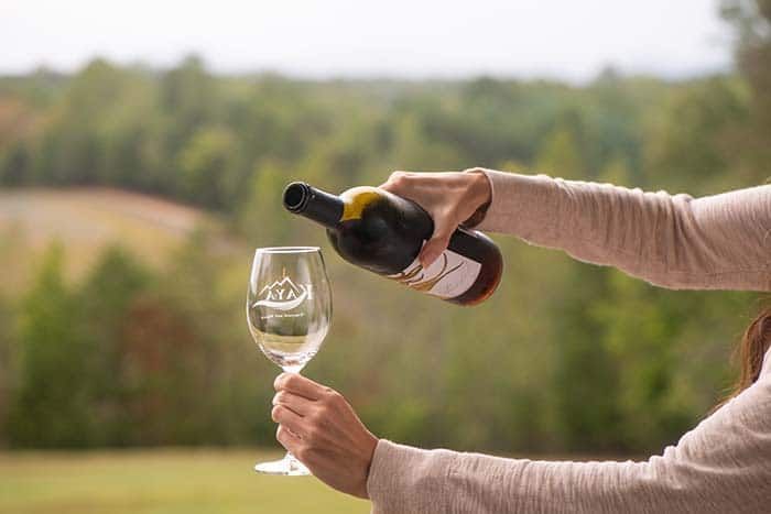 A woman is pouring wine into a glass.