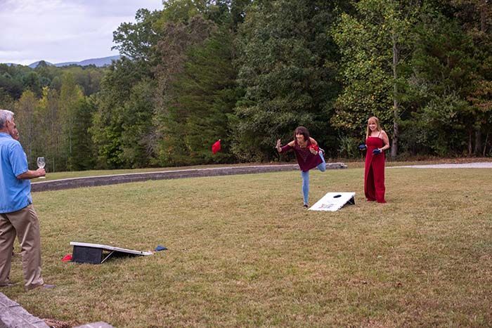 A group of people are playing a game of cornhole in a grassy field.