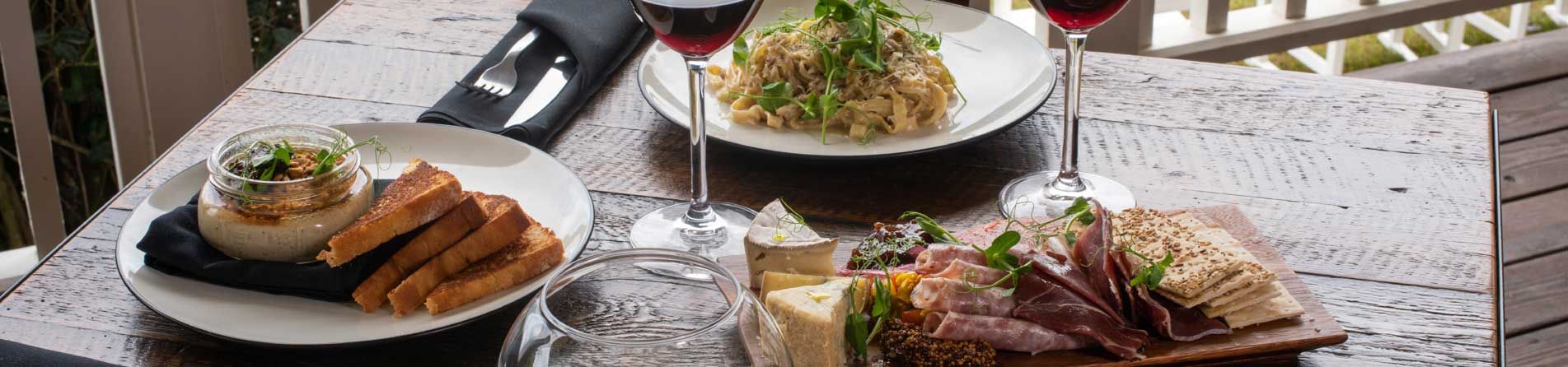 A table topped with plates of food and wine glasses.
