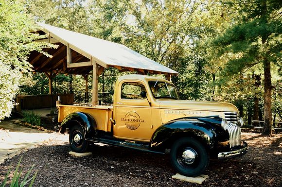 A yellow truck is parked under a roof in the woods
