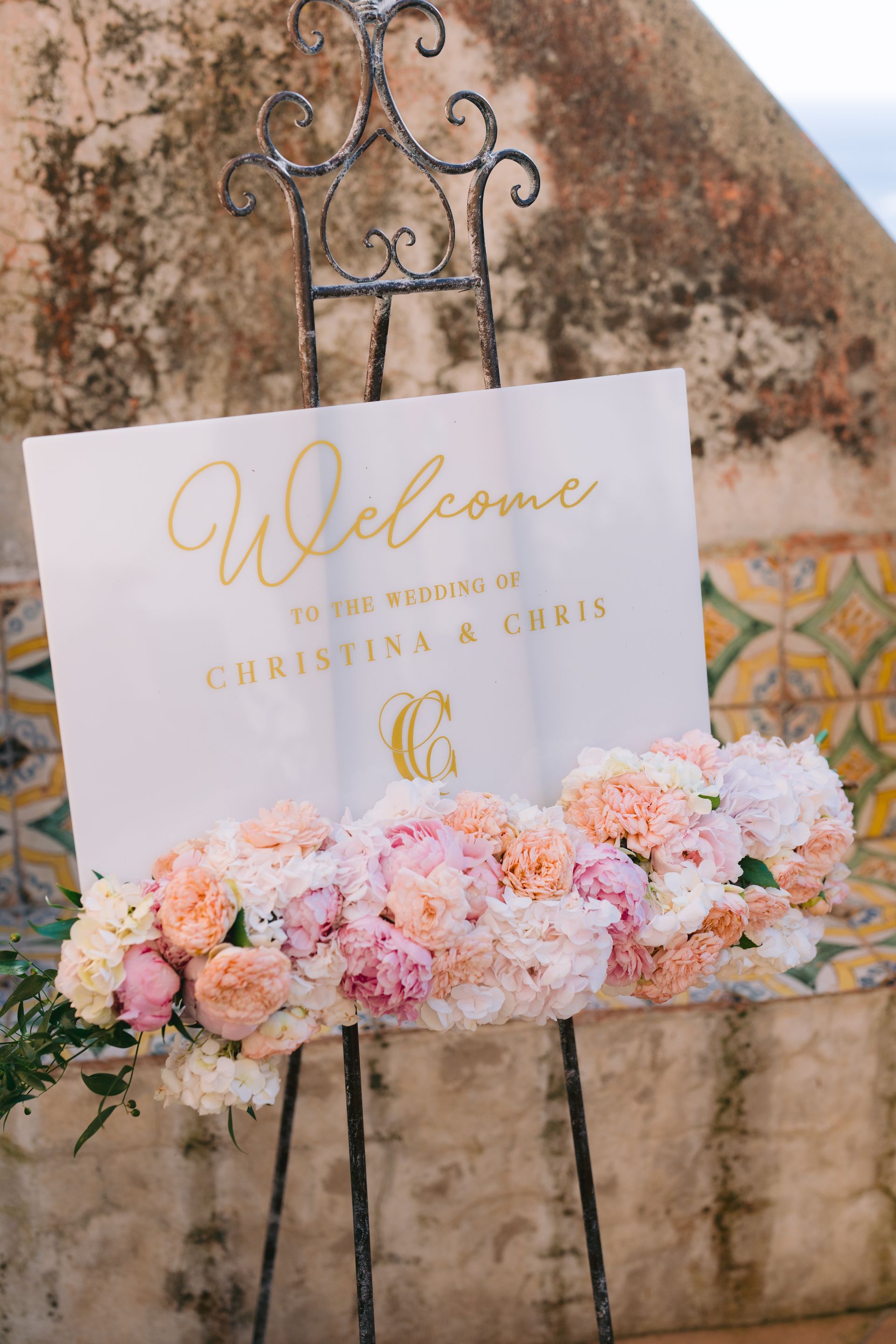 A welcome sign is sitting on top of an easel surrounded by flowers.