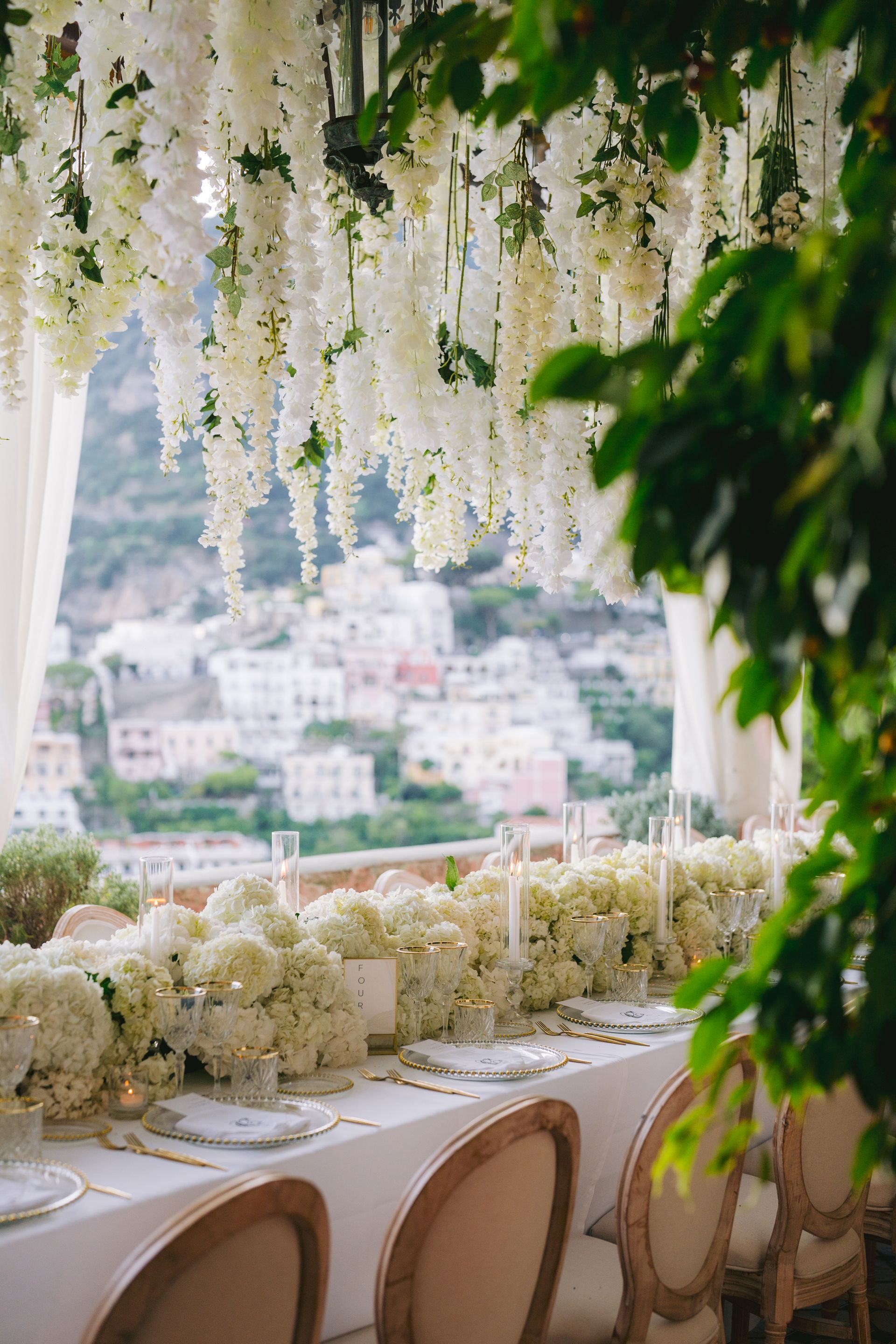 A long table with white flowers hanging from the ceiling.