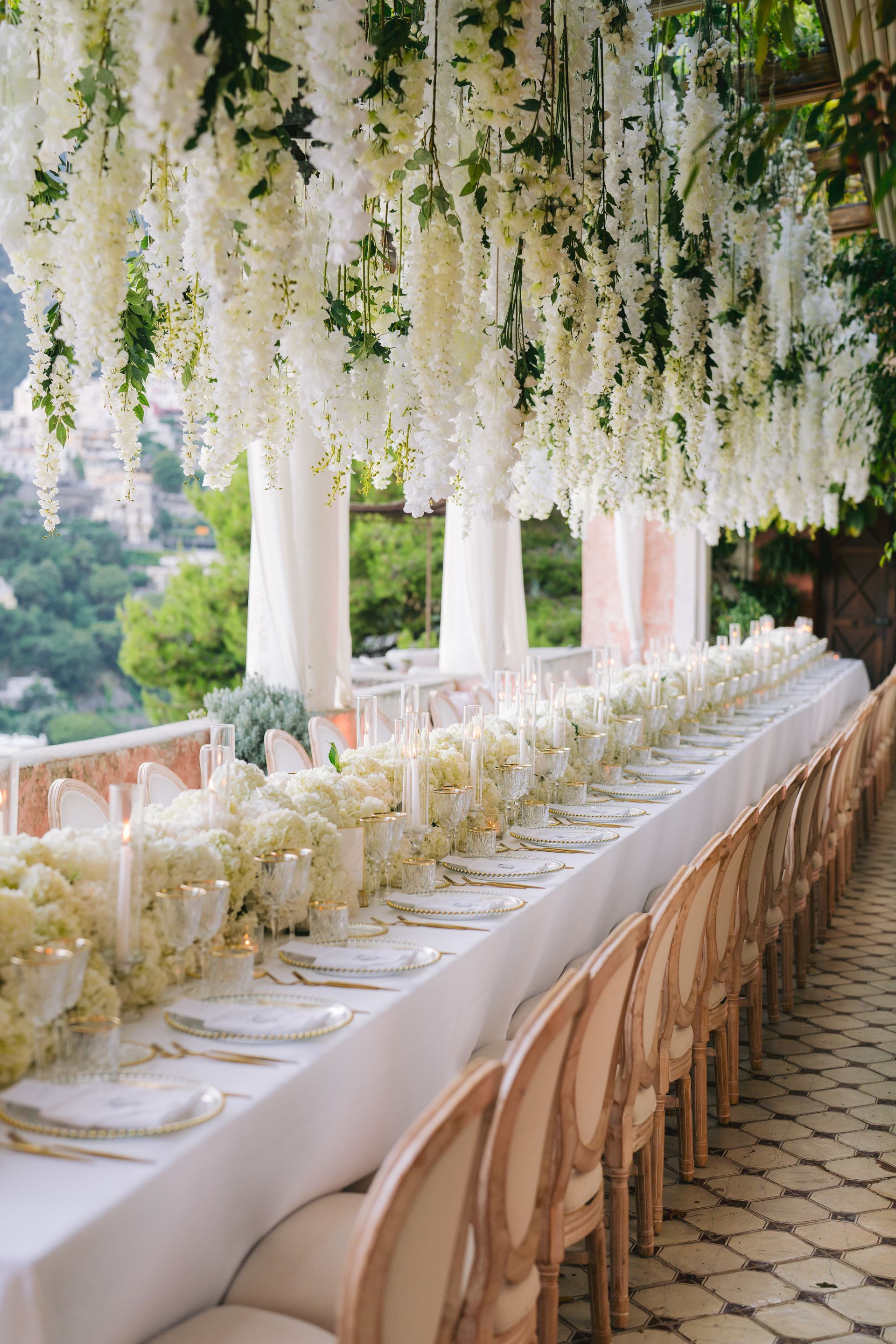 A long table with white flowers hanging from the ceiling.