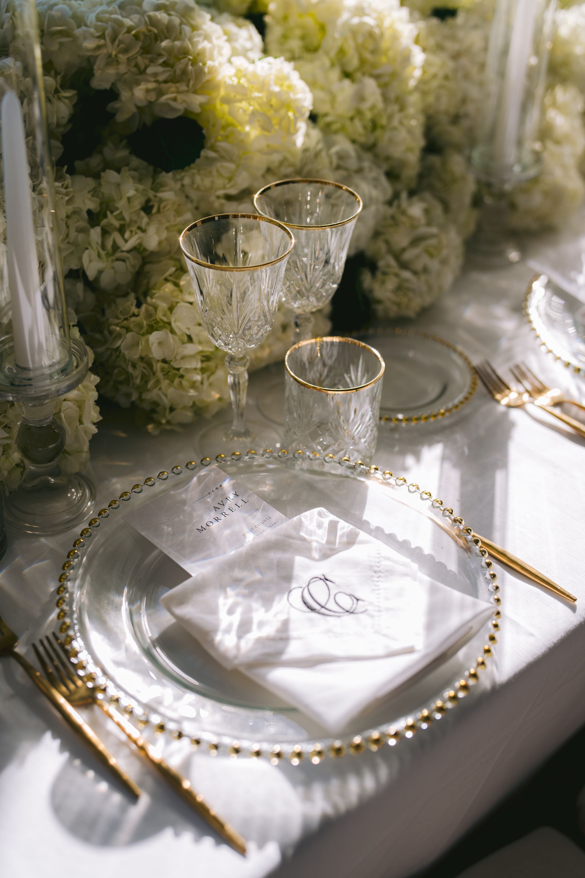 A table set for a wedding reception with plates , glasses , silverware and flowers.