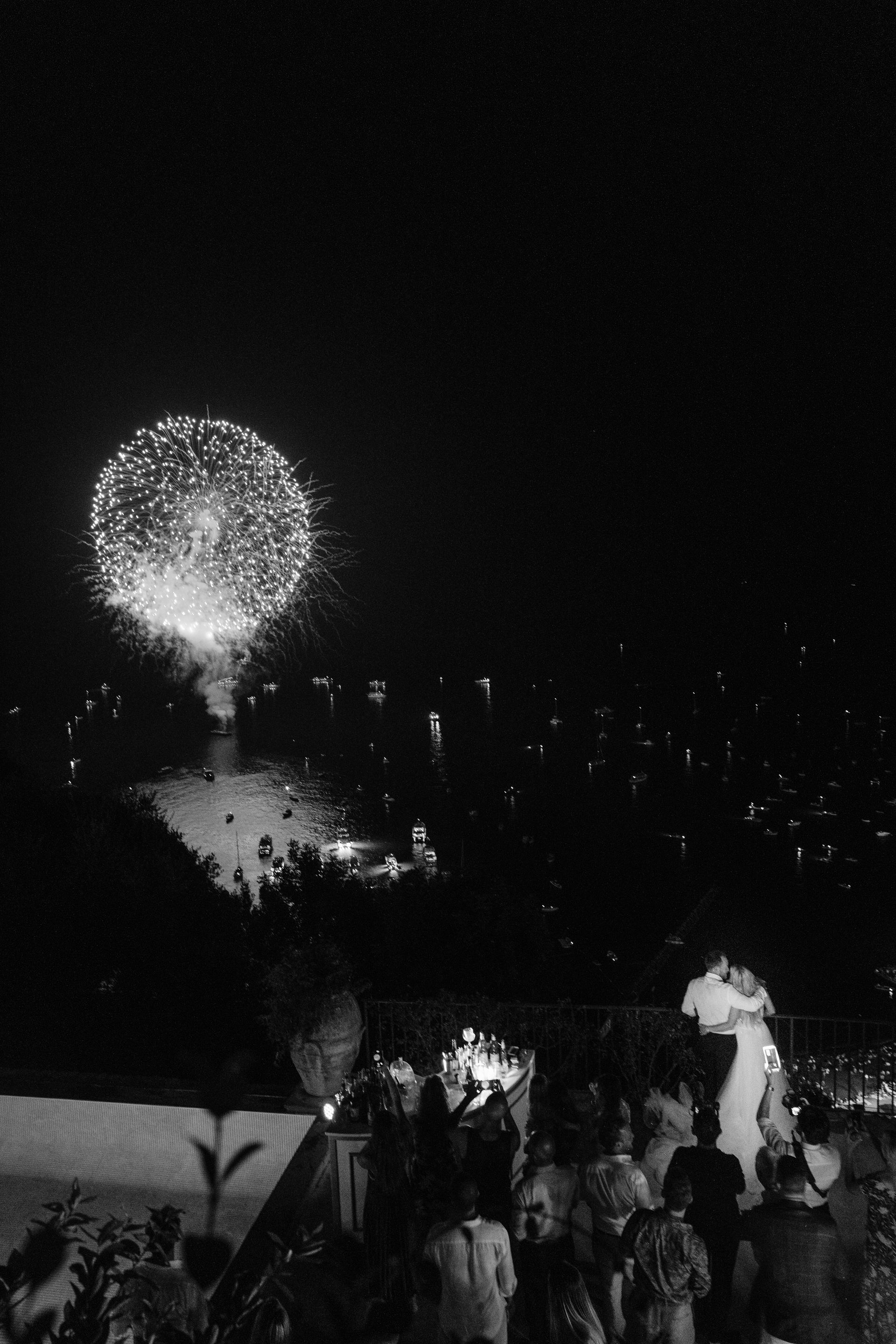 A black and white photo of a crowd watching fireworks.