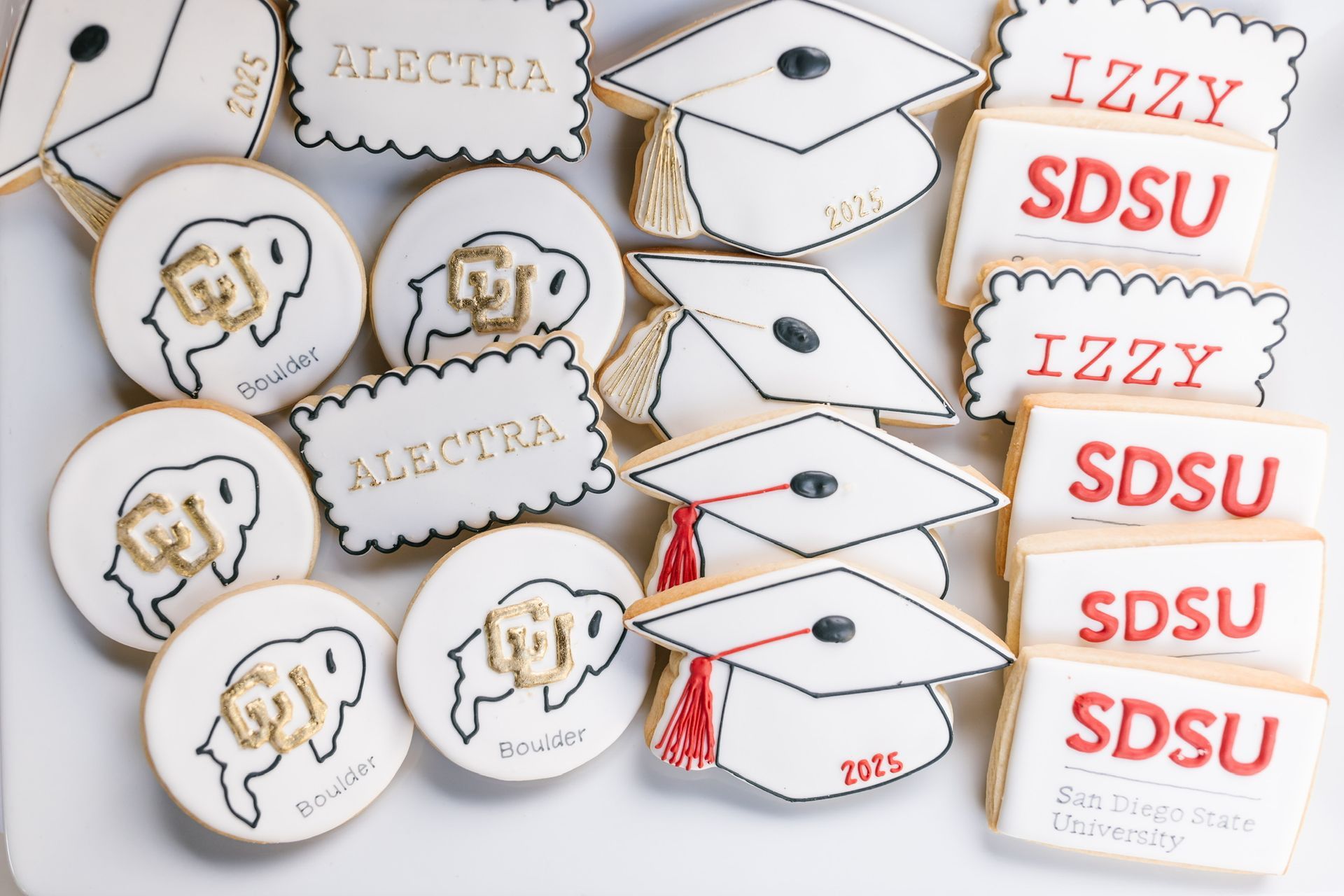 A bunch of graduation cookies with the name alectra on them.