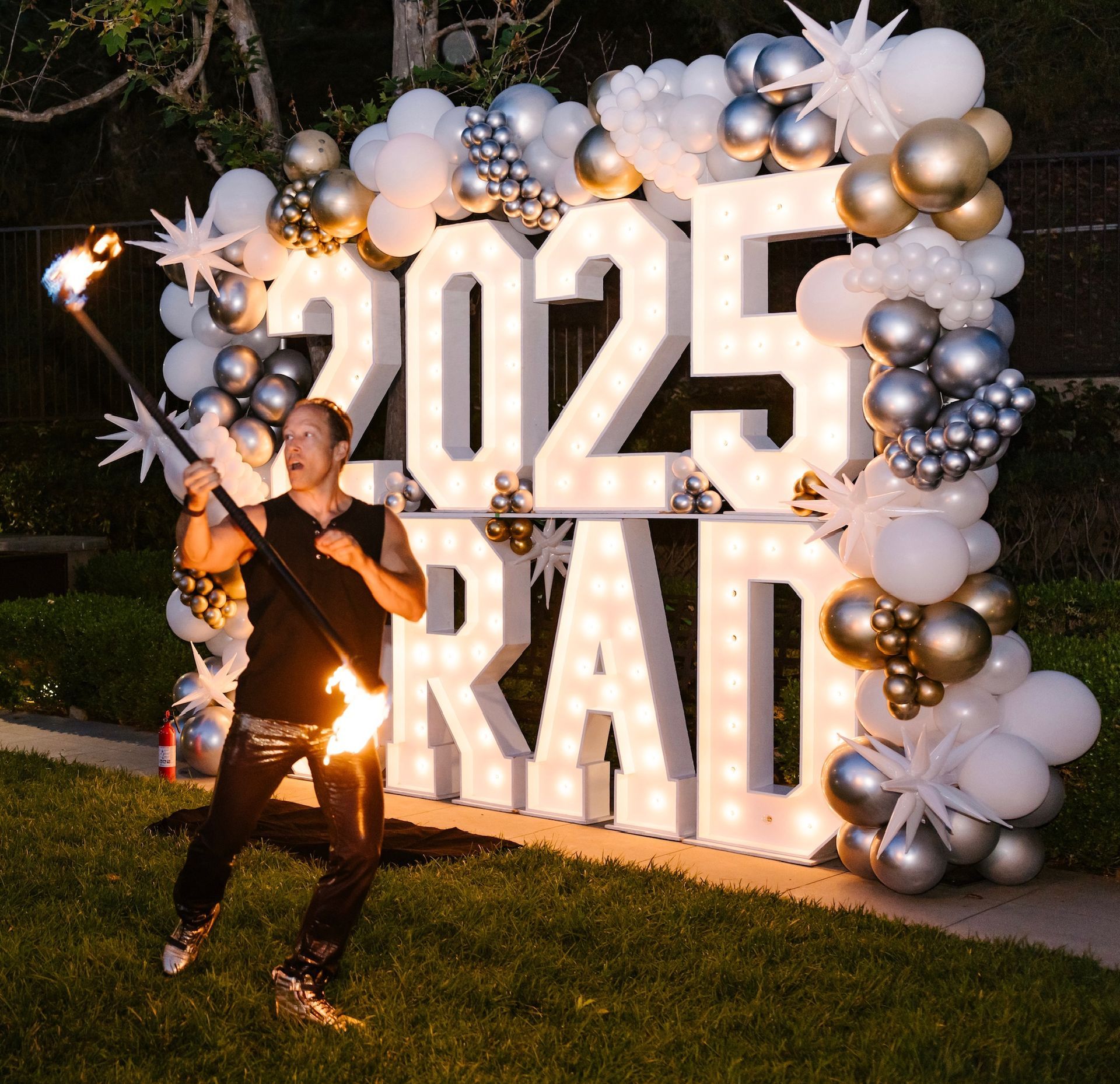 A man is holding a torch in front of a sign that says 2025 grad.