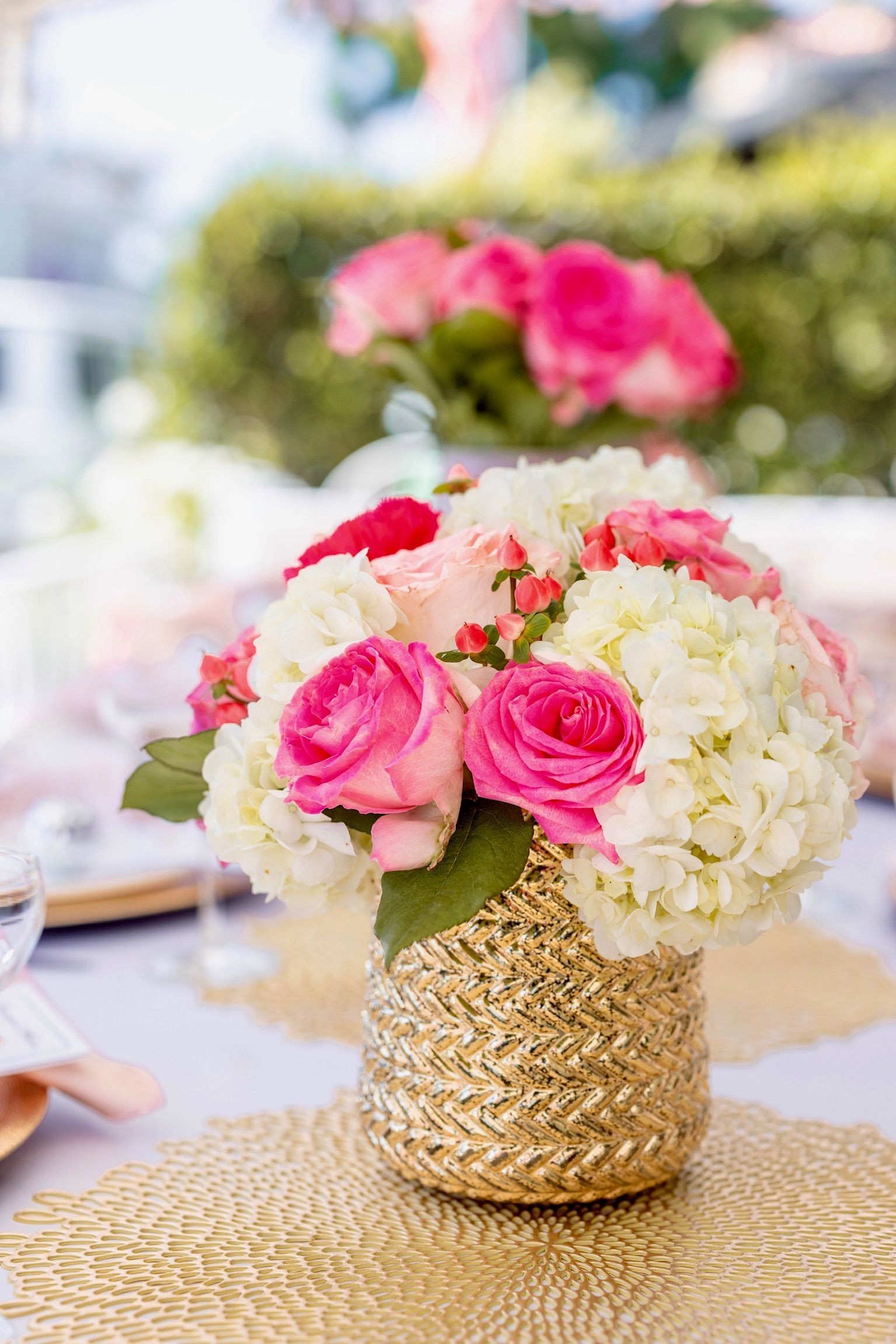 A gold vase filled with pink and white flowers on a table.