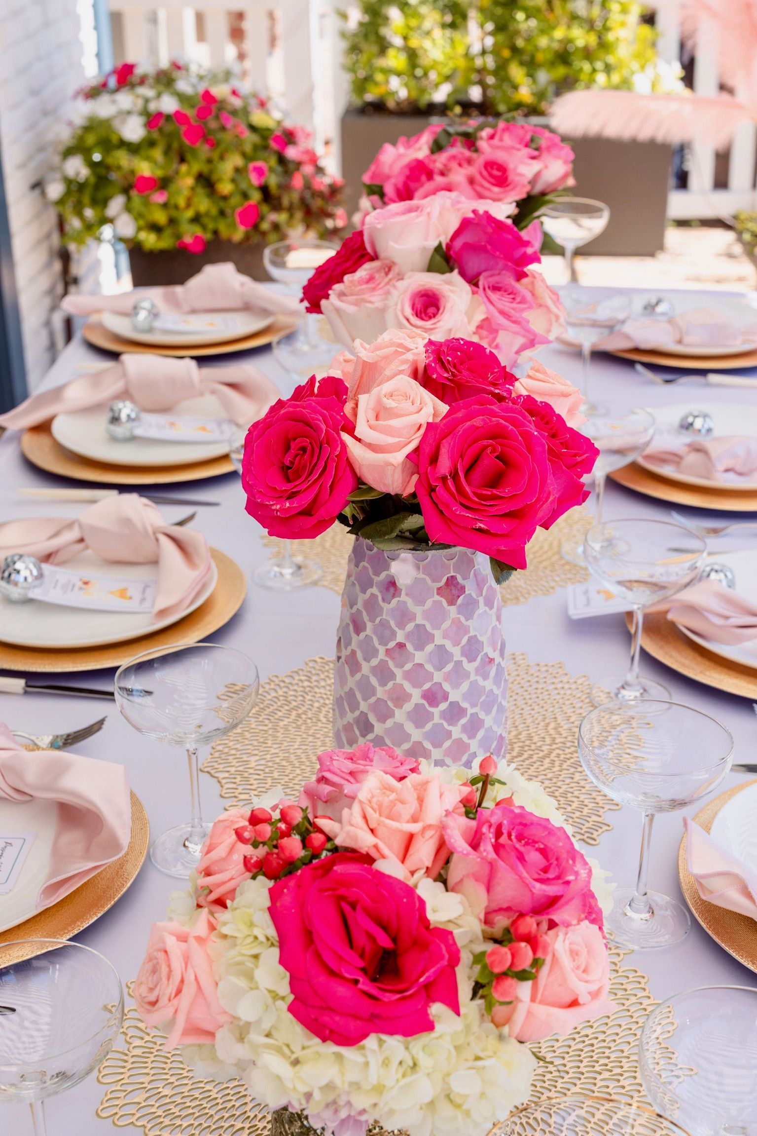 A table set for a party with pink flowers in vases.