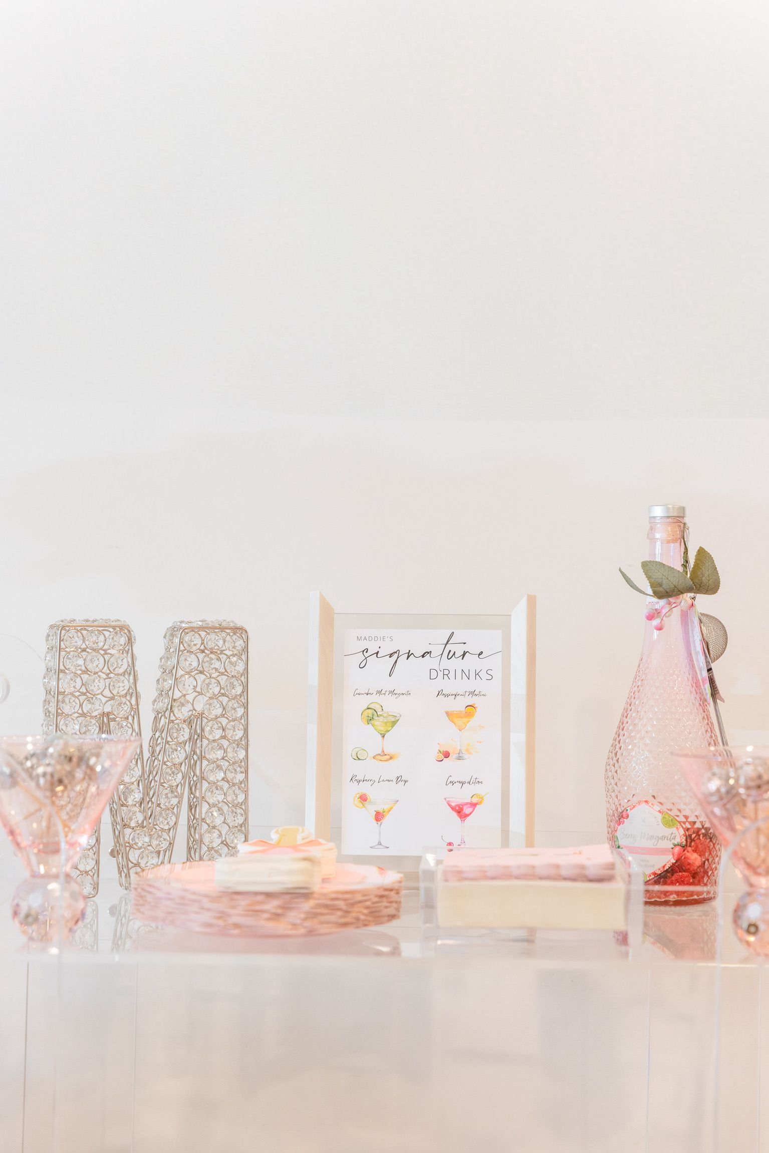 A table with a cake , bottles , glasses , and a picture on it.