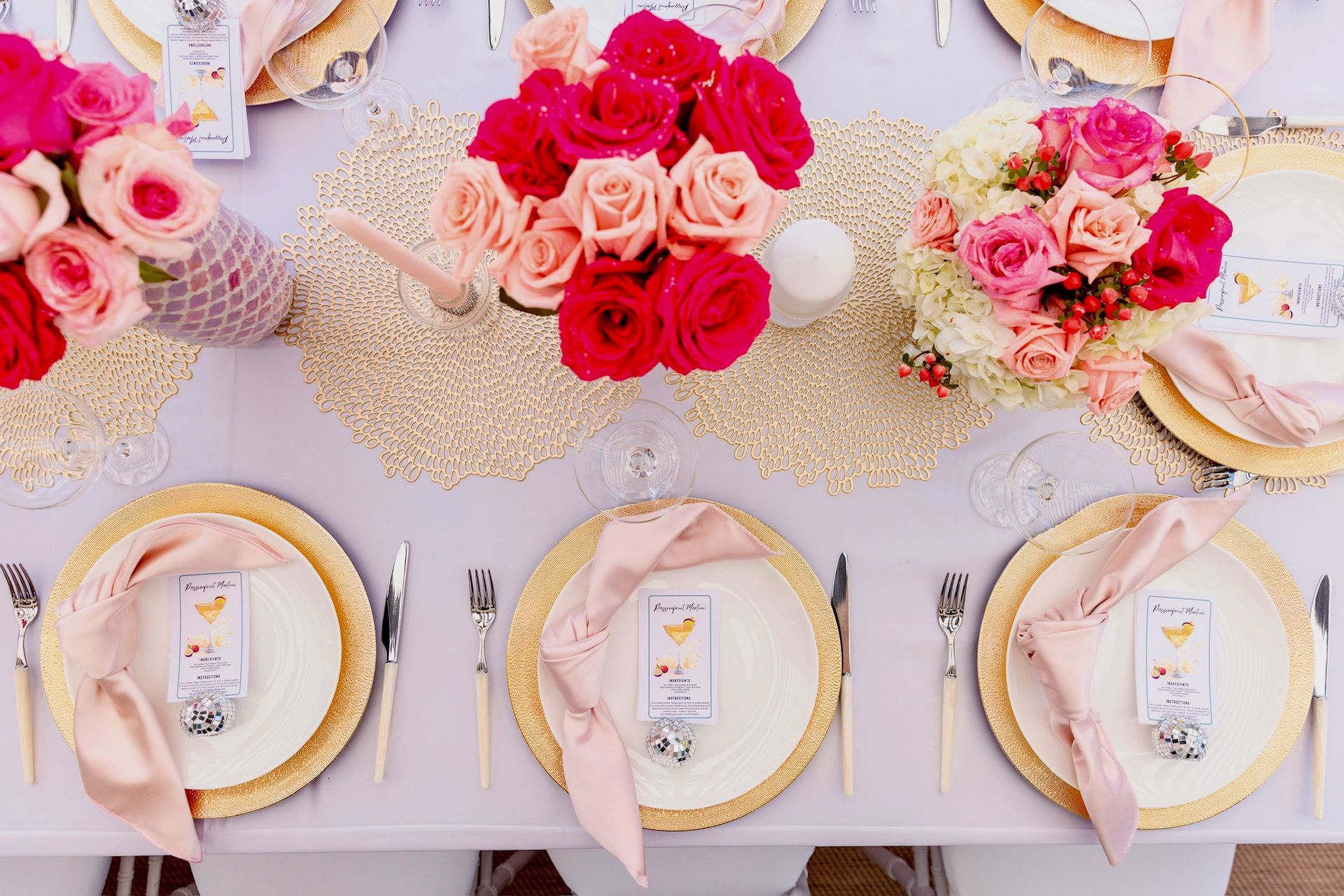 A table with plates , napkins , utensils and flowers on it.
