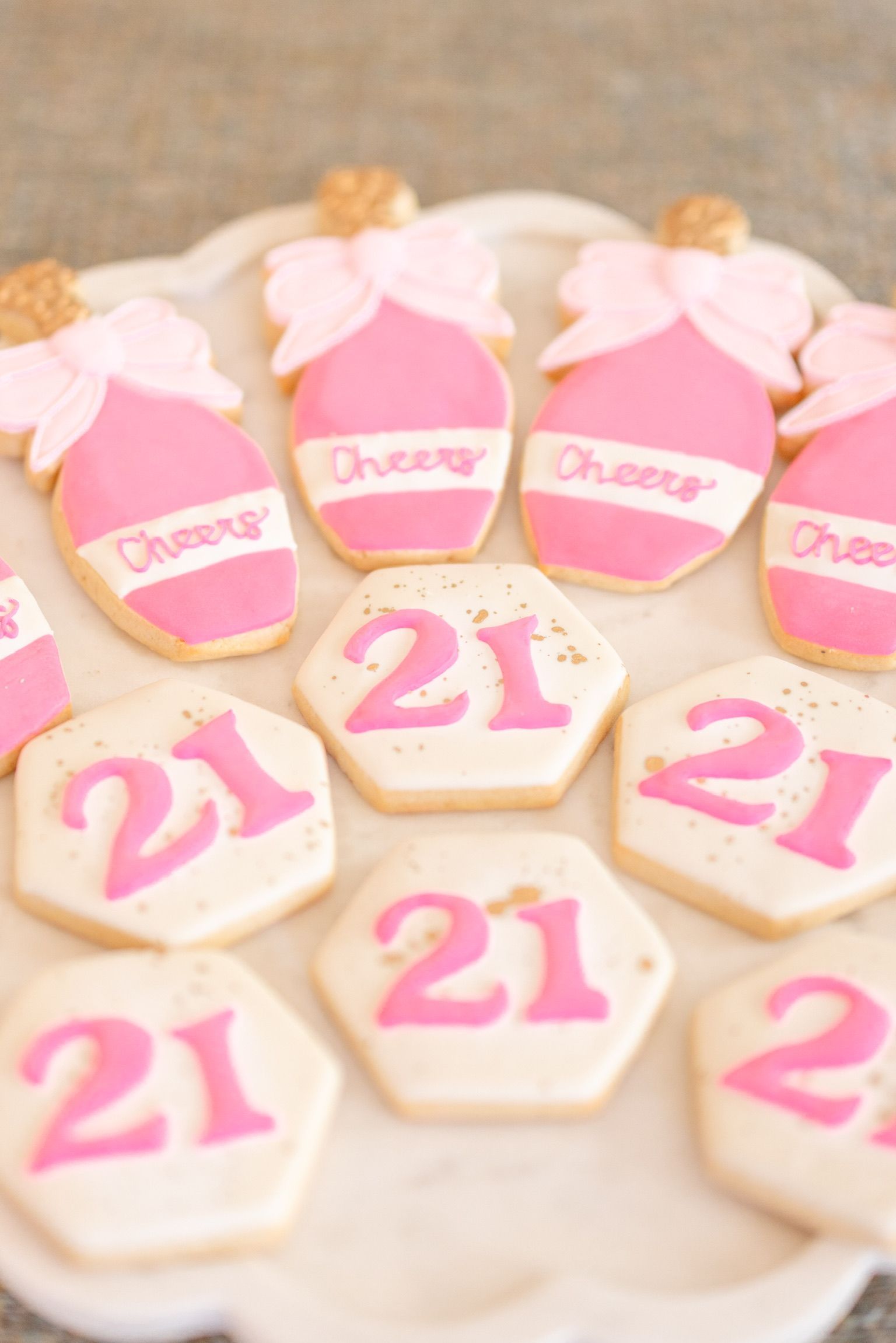 A plate of pink and white cookies with the number 21 on them.