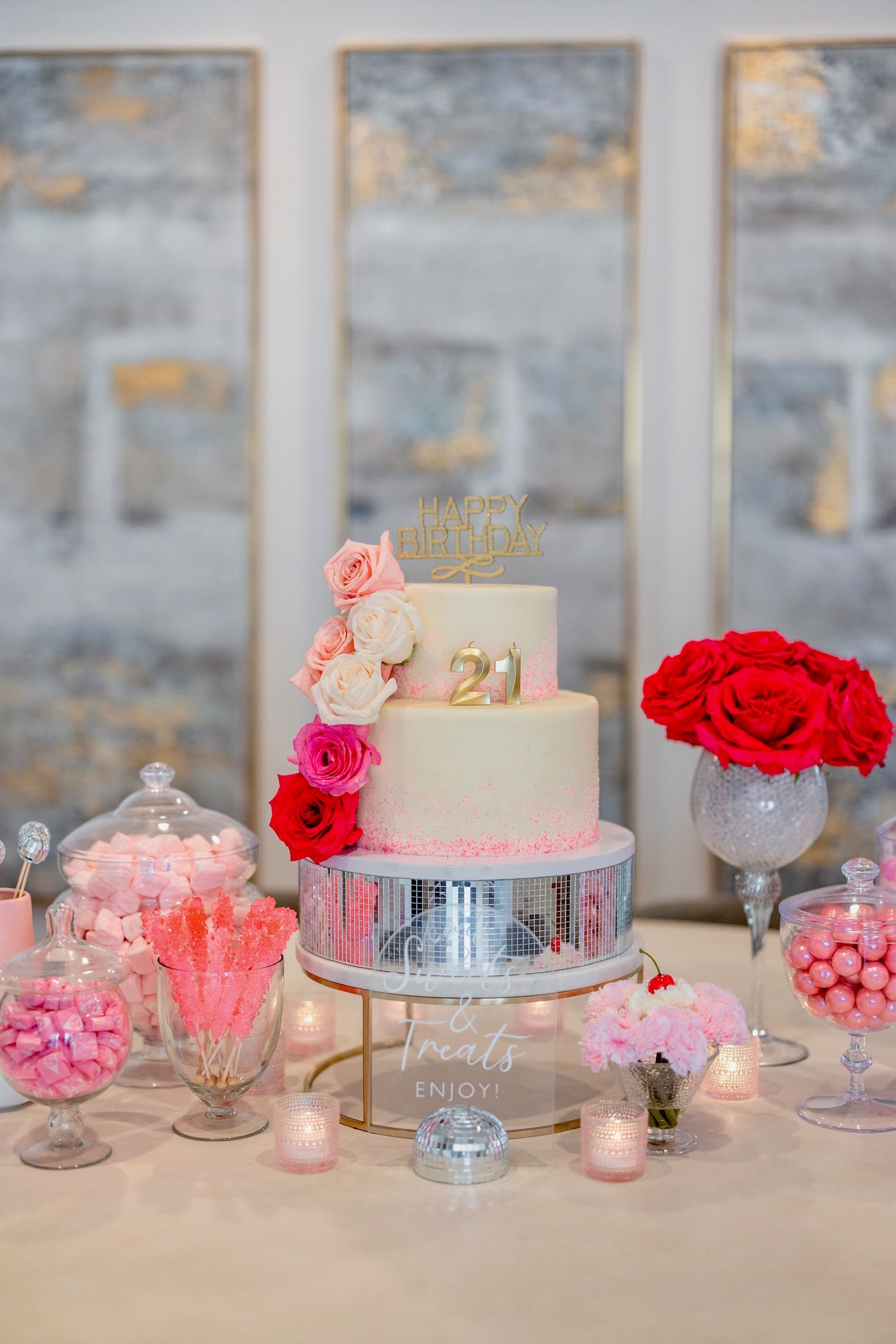 A wedding cake is sitting on top of a table surrounded by candy and flowers.