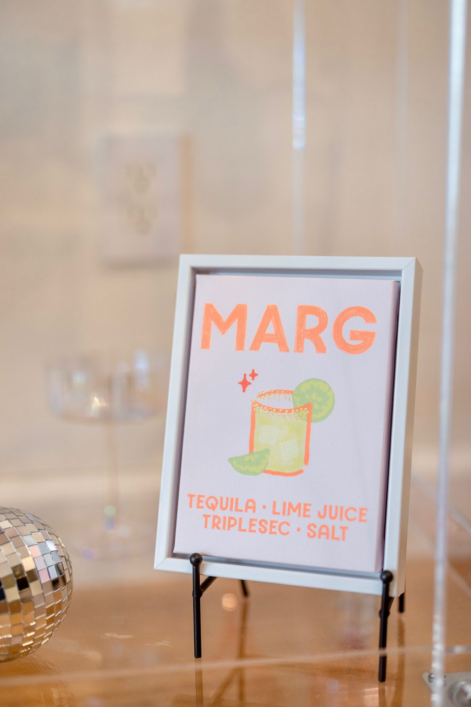 A sign for a margarita is sitting on a wooden table.