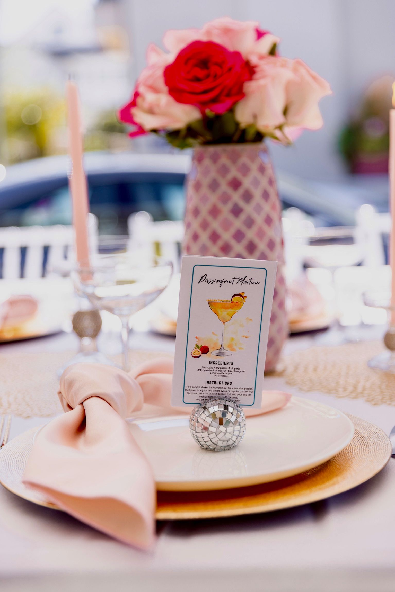 A table setting with plates , napkins , candles and a vase of flowers.