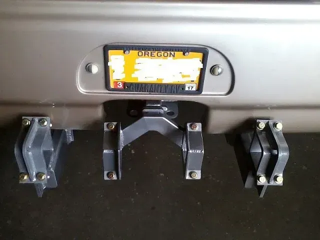 Close-up of a vehicle's rear bumper with an Oregon license plate and black mounting brackets.
