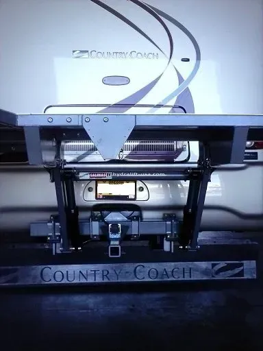 Rear view of a Country Coach RV, showing the bumper with a trailer hitch, license plate, and brand name.