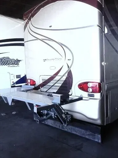 Back of RV with a silver ramp, red tail lights, and a decorative swirl design.