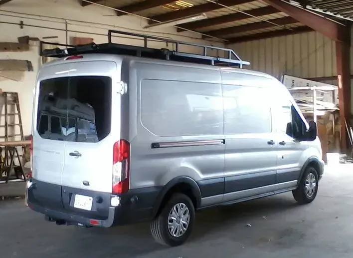 Silver Ford Transit van with roof rack, parked inside a workshop.
