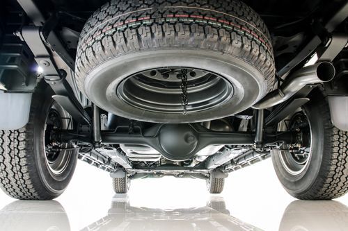 Undercarriage of a black truck, spare tire visible, against a white background.