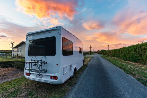 White RV parked on a road with a colorful sunset sky.