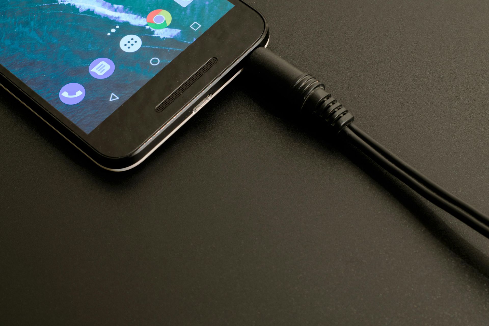 A cell phone is plugged into a charger on a table.