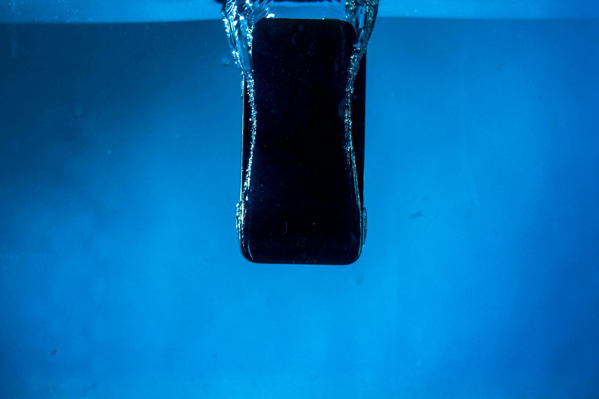 A cell phone is being dropped into a pool of water.