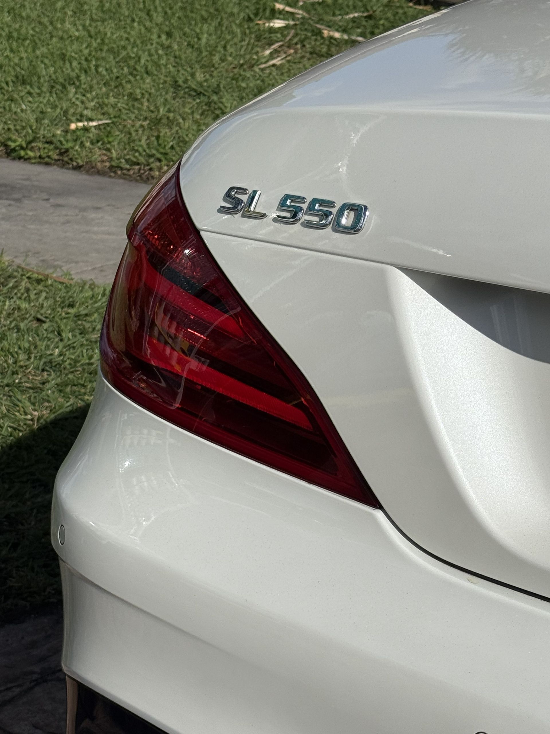 Close-up of the rear corner of a white Mercedes-Benz SL 550, showing the taillight and model emblem.